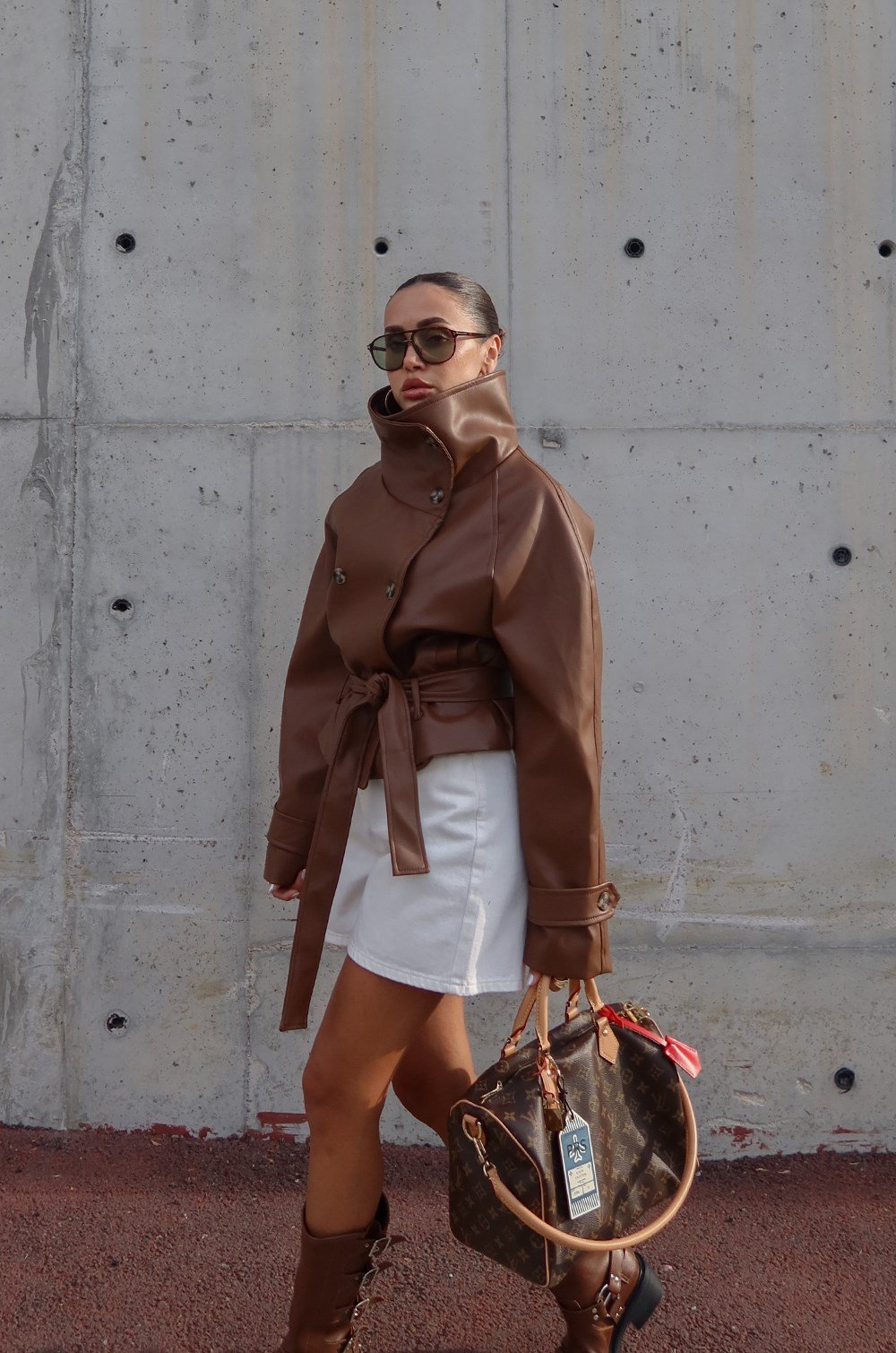 Brown faux leather jacket with its dramatic high funnel collar and matching tie belt.