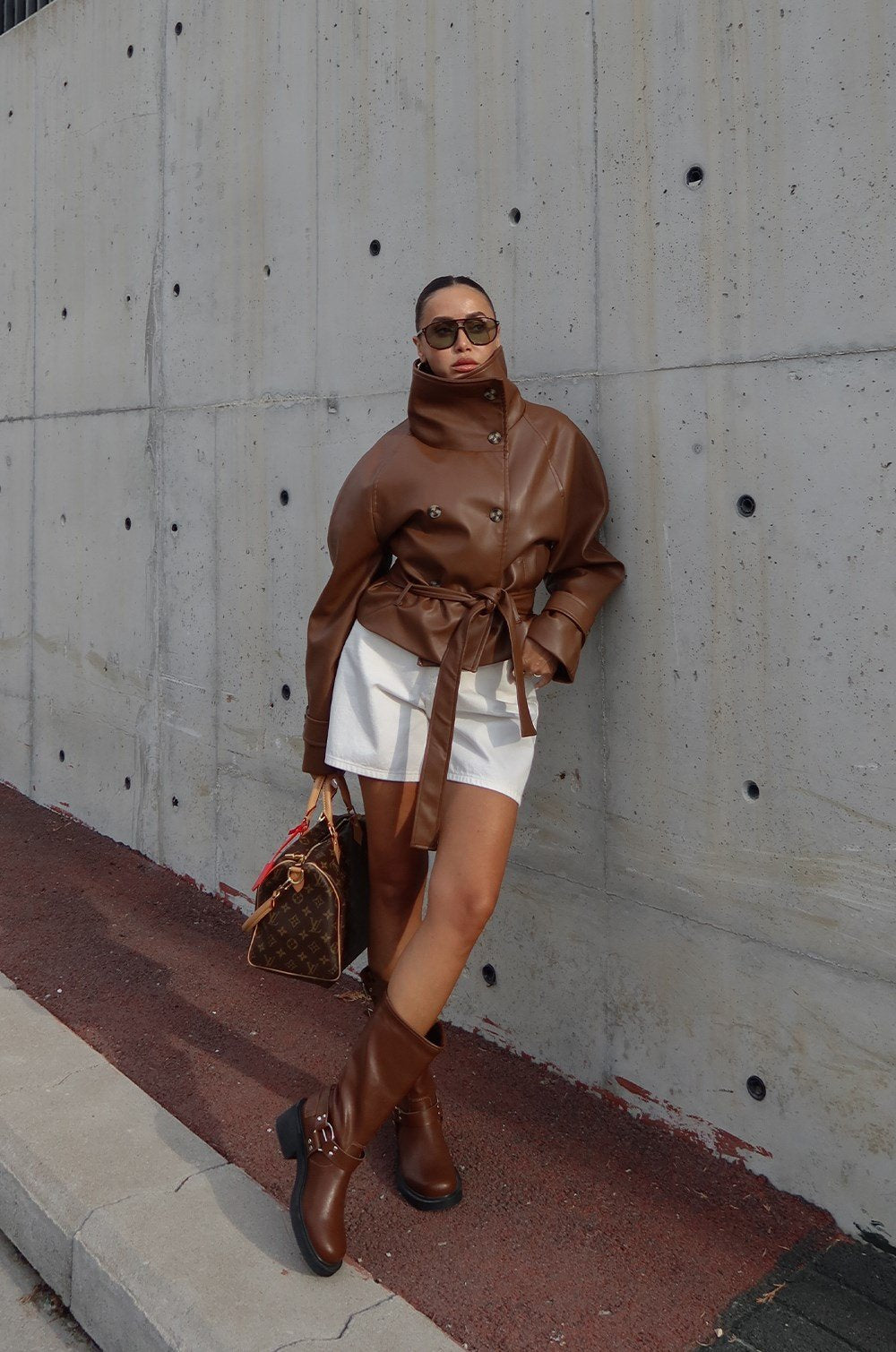 Brown faux leather jacket with its dramatic high funnel collar and matching tie belt.